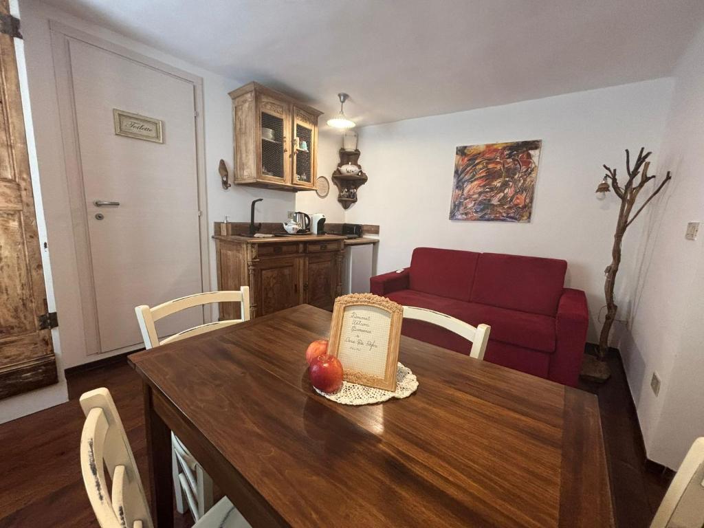 a living room with a table and a red couch at Casa Di Orfea in Perosa Argentina