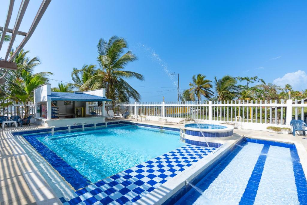 a swimming pool with blue tiles in front of a fence at Blue Apartahotel Coveñas in Coveñas