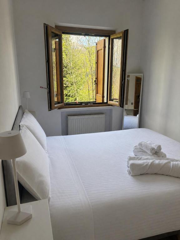a white bed in a room with a window at Cozy Mountain Apartment with Cimone view in Faidello