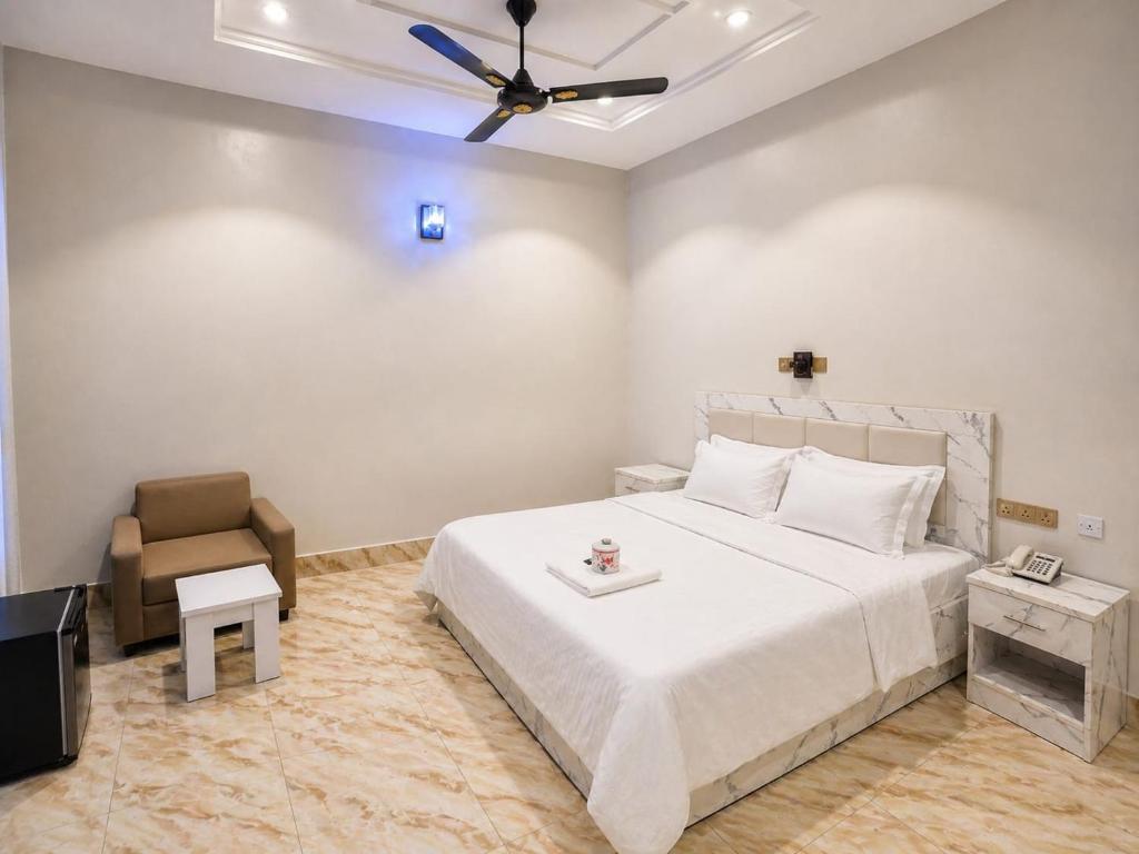 a bedroom with a large white bed and a chair at The Whale Inn Narayi rd Barnawa high cost in Kaduna