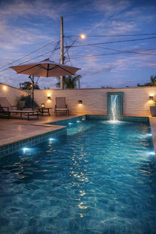 a swimming pool with a fountain and an umbrella at Sweet Home Away from yours in Lagoa Santa