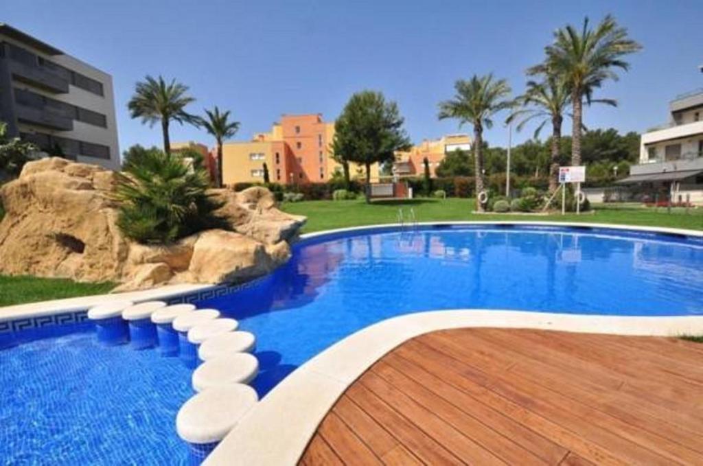 una gran piscina con terraza de madera junto a un edificio en J Tramuntana Planet Costa Dorada, en Salou