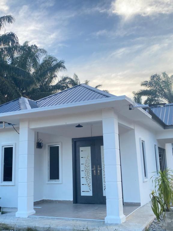a small white home with a black door at Singgah Salam Stay in Parit Raja
