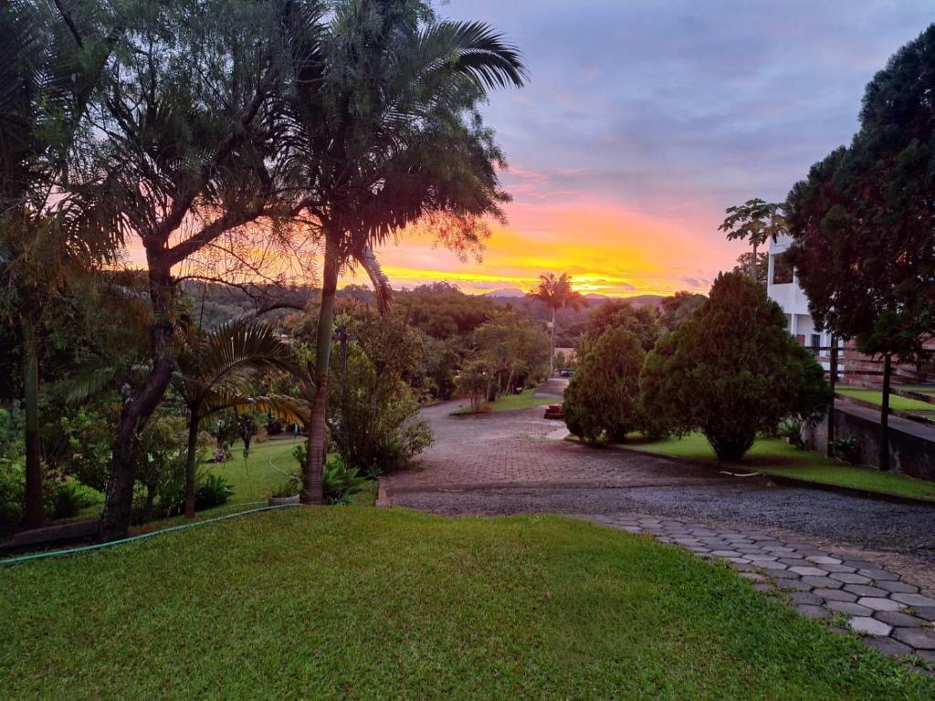 a sunset over a park with palm trees and a pathway at Pousada Efraim in Tiradentes