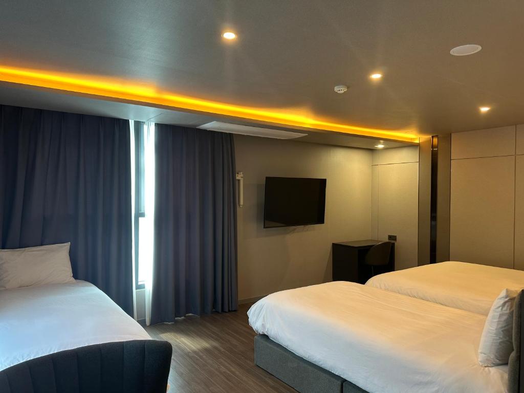 a hotel room with two beds and a flat screen tv at The Western Busan Hotel By STAYNEO in Busan