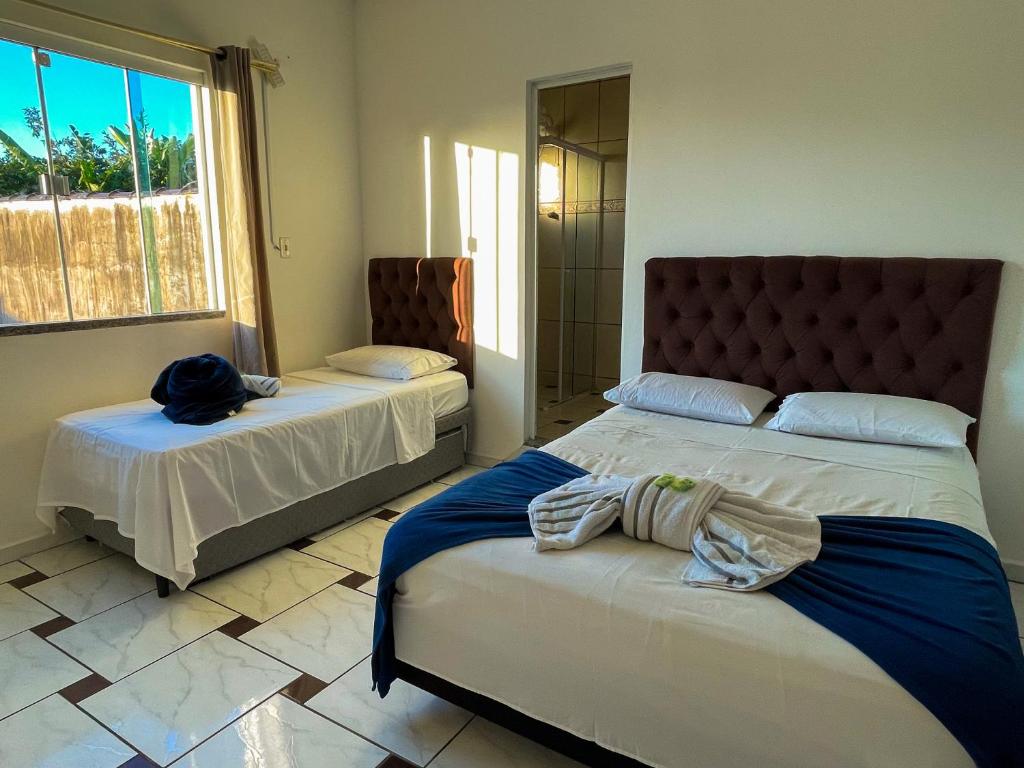 a bedroom with two beds and a large window at Pousada Mel e Mar in Penha