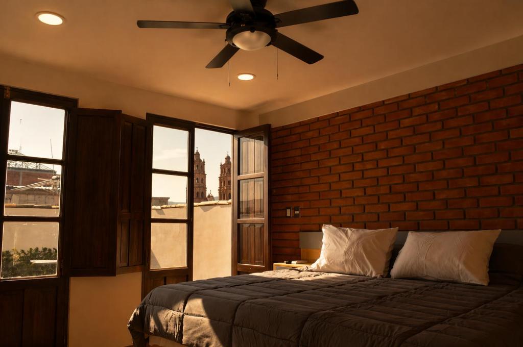 a bedroom with a ceiling fan and a brick wall at El Suburbio - Serapio Rendon in Morelia