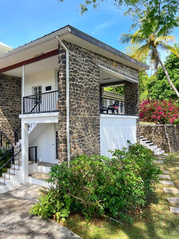 a brick house with a balcony and a palm tree at Bungles Ungalow in Castries