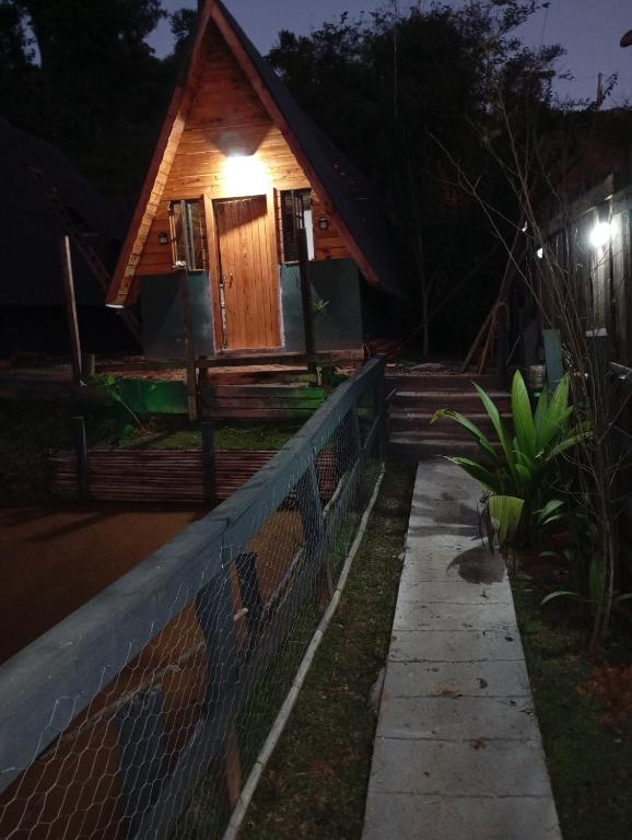 a house with a fence in front of it at night at Chalés FRONT LAKE 1 in Córrego do Bom Jesus
