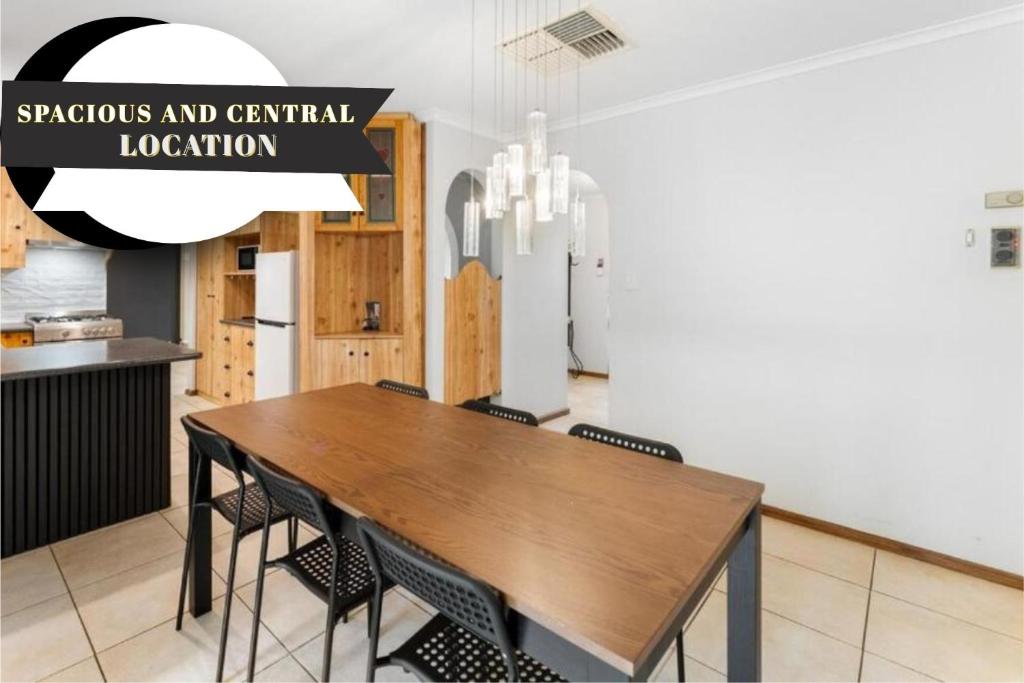 a dining room with a wooden table and chairs at Private 4BR Garden Haven - Spacious & Serene in Mawson Lakes