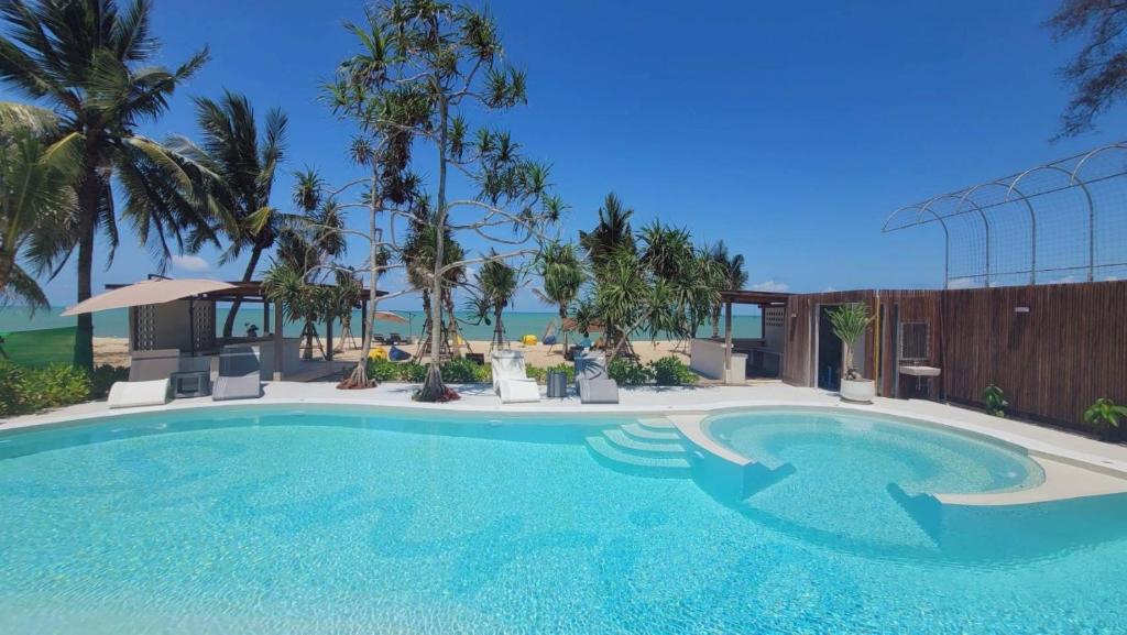 a large swimming pool in a resort with palm trees at Sunrio Beach Hotel Sichon in Ban Plai Thon