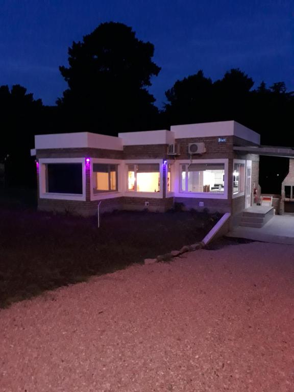 una casa iluminada por la noche con luces púrpuras en Complejo Sol&Luna en Villa Ventana
