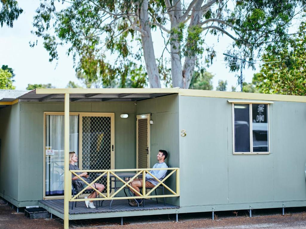two people sitting on the balcony of a tiny house at Collie Tourist Park in Collie