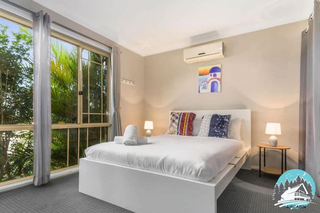 a bedroom with a white bed and a large window at 3B house Central Coast parking in Blue Haven