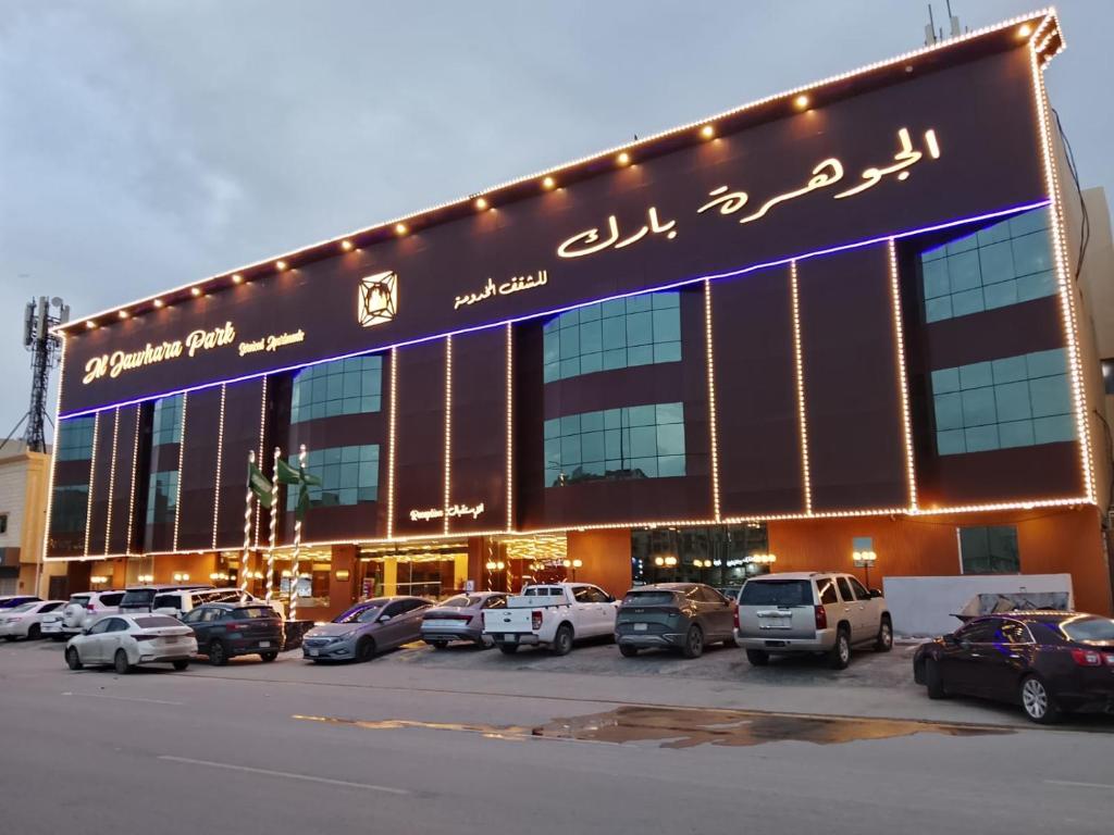 a large building with cars parked in a parking lot at الجوهرة بارك للشقق المخدومة 6 in Riyadh