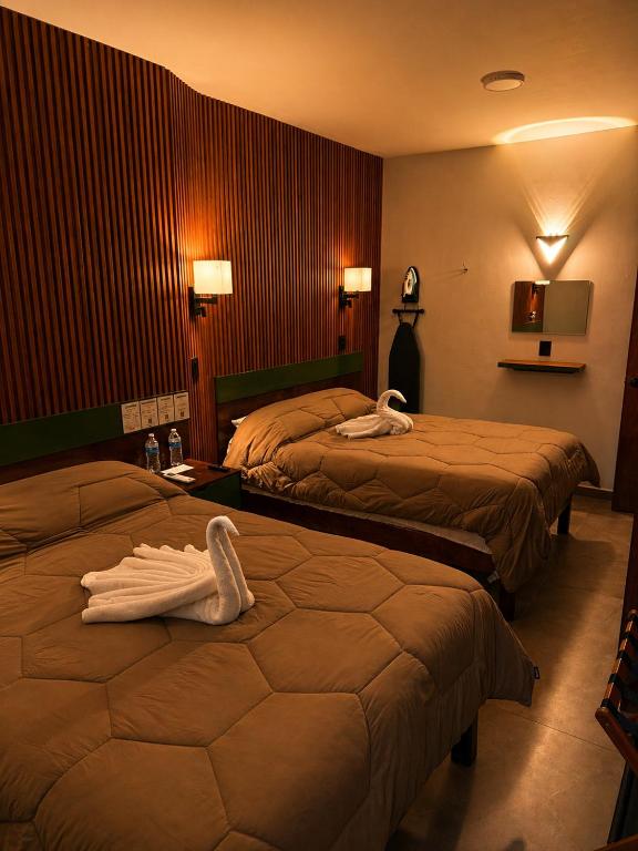 a hotel room with two beds with towels on them at El Suburbio - Aldama in Morelia