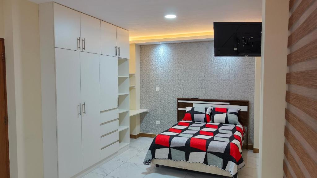 a bedroom with a bed and a tv on a wall at Hospedaje Smart Wasi Sucre in Sucre