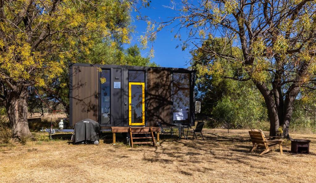 a tiny house sitting in a field with trees at Auburn Vale Cottage by Tiny Away in Quirindi