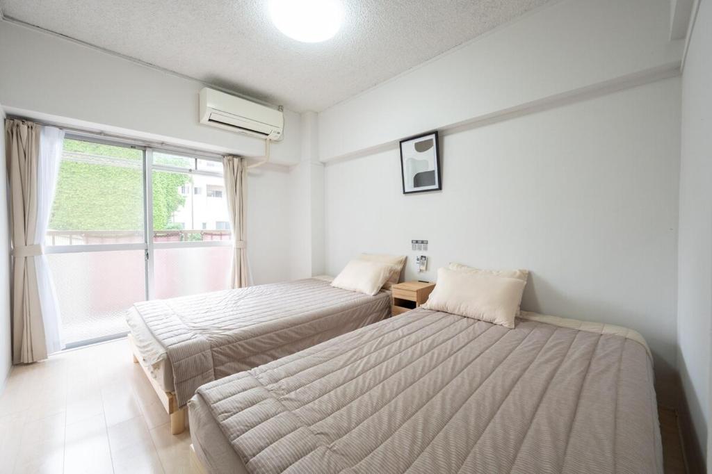 a bedroom with two beds and a window at GoodStay505 in Kurume