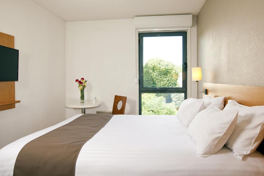 a bedroom with a large white bed with a window at Séjours & Affaires Orléans Jeanne D'Arc in Orléans