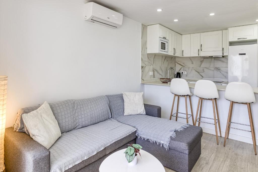 a living room with a couch and a kitchen at Apto Nidos cerca de la playa in L'Escala