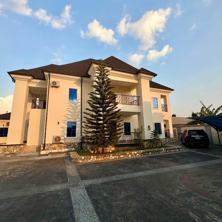 a large house with a tree in a parking lot at perficient apartments in Okpanam