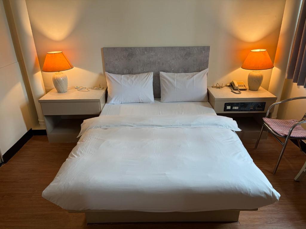 una camera da letto con un grande letto bianco e due lampade di 東城年代旅舍中山館 a Taichung