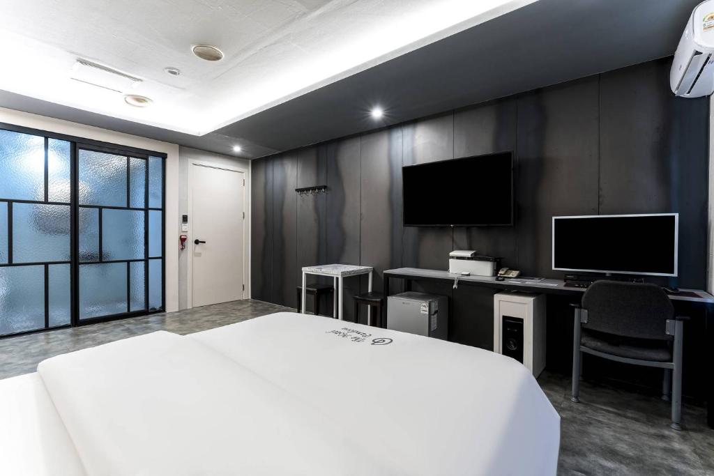 a bedroom with a bed and a desk with a monitor at Pandora Hotel in Hwaseong