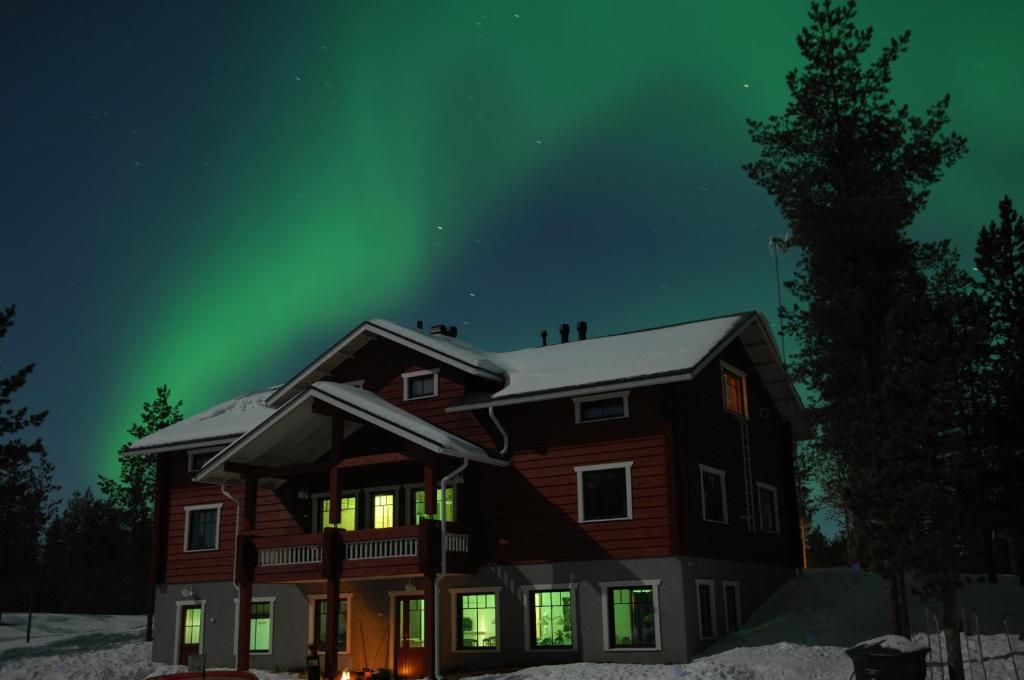 a house with the aurora in the sky at Guesthouse Husky in Ivalo