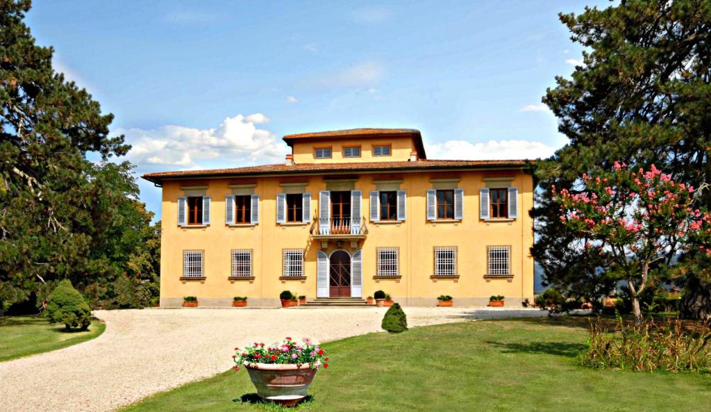 a large yellow house with a yard with flowers at Villa I Delfini in Vicchio
