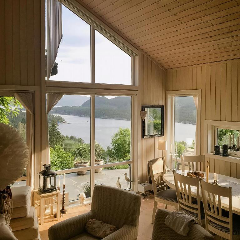 a living room with a table and chairs and a large window at Cozy Cabin With Økstrafjord View in Jelsa