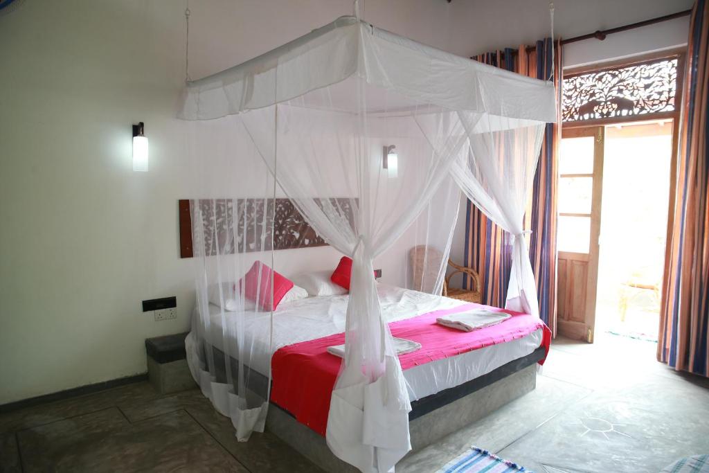 a bedroom with a canopy bed with a red blanket at Mary's Palm Garden in Hikkaduwa