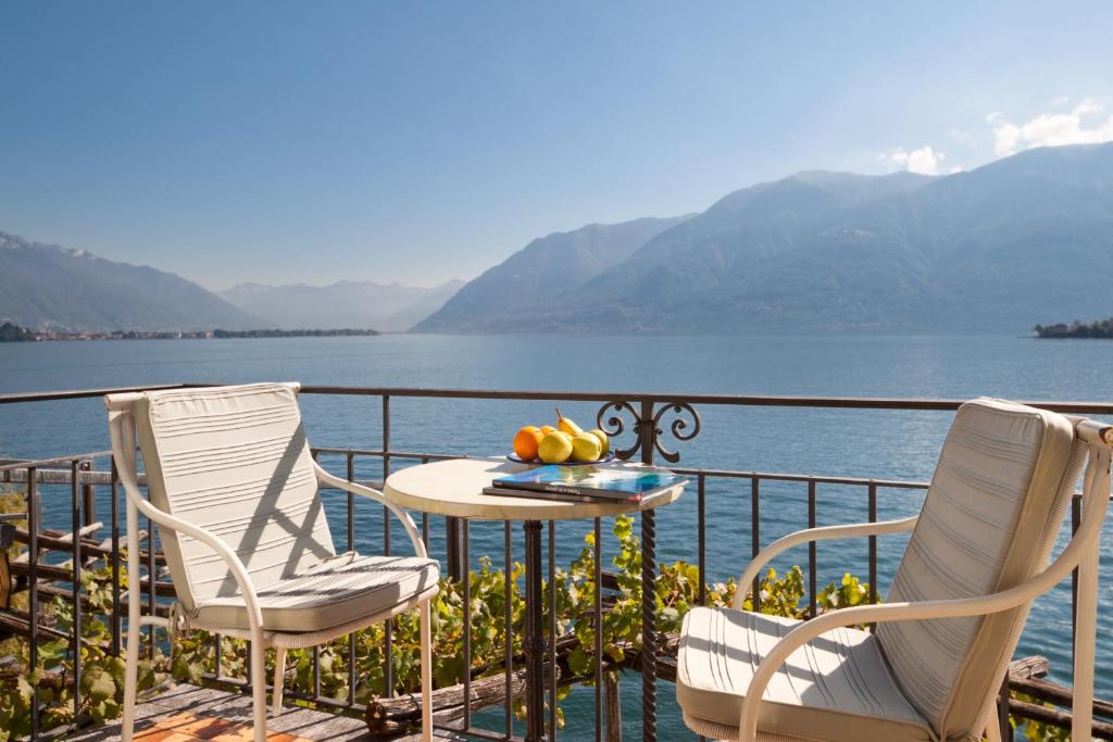 ロンコ・ソプラ・アスコナにあるArt Hotel Ristorante Posta Al Lagoのテーブルと椅子、水辺の景色を望むバルコニー