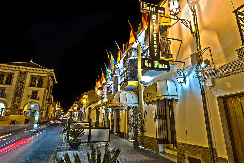 un edificio con banderas al lado de una calle en Hotel La Pinta en Palos de la Frontera