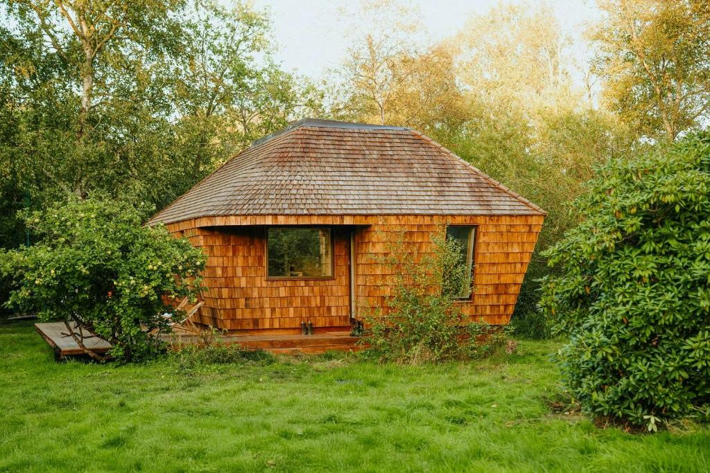 a small log cabin with a bench in a field at Architectural Tiny House With Sauna Near Beach in Asnæs
