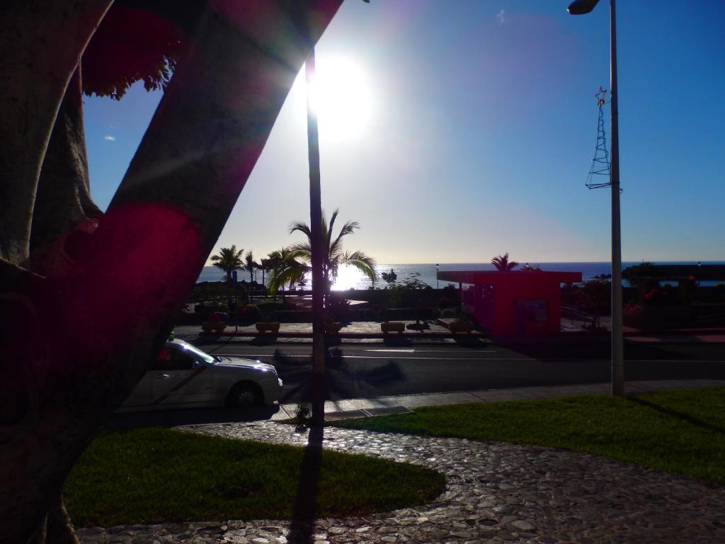 a sun is setting in a parking lot with a palm tree at Edificio Orion in Tazacorte