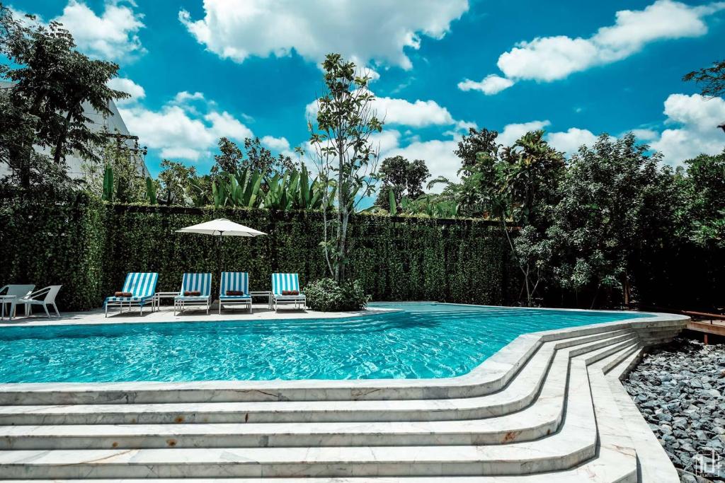 a swimming pool with two chairs and an umbrella at Parc Borough City Resort in Chiang Mai