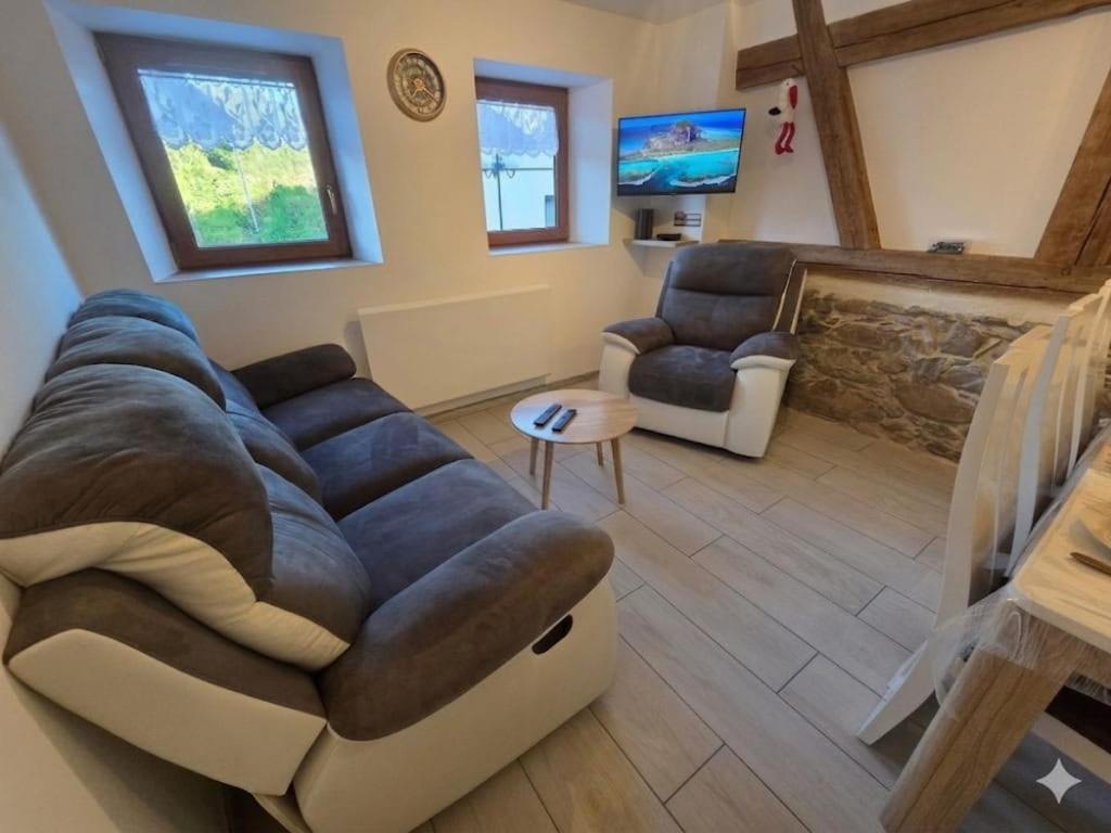 a living room with a large couch and a tv at La vallée de la bruche in Wisches