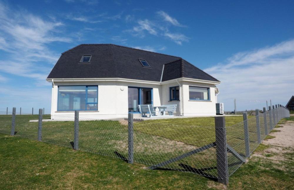 a small white house on a hill with a fence at Gualan Sands in Clachan