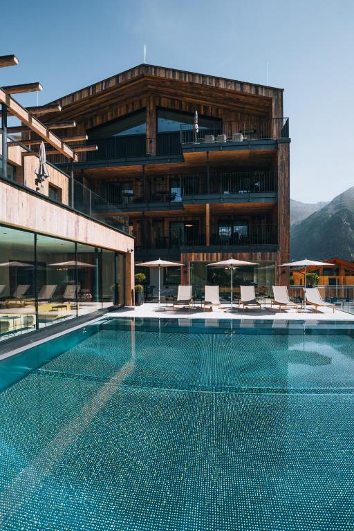 a swimming pool in front of a building at Grünwald Resort Sölden Appartements und Chalets mit Pool in Sölden