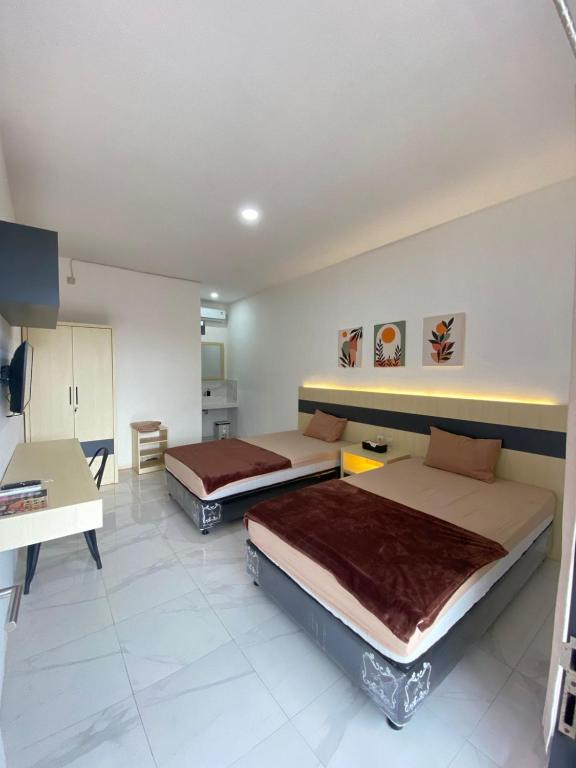 a room with two beds and a desk and a kitchen at Kims Stay Syariah in Jember