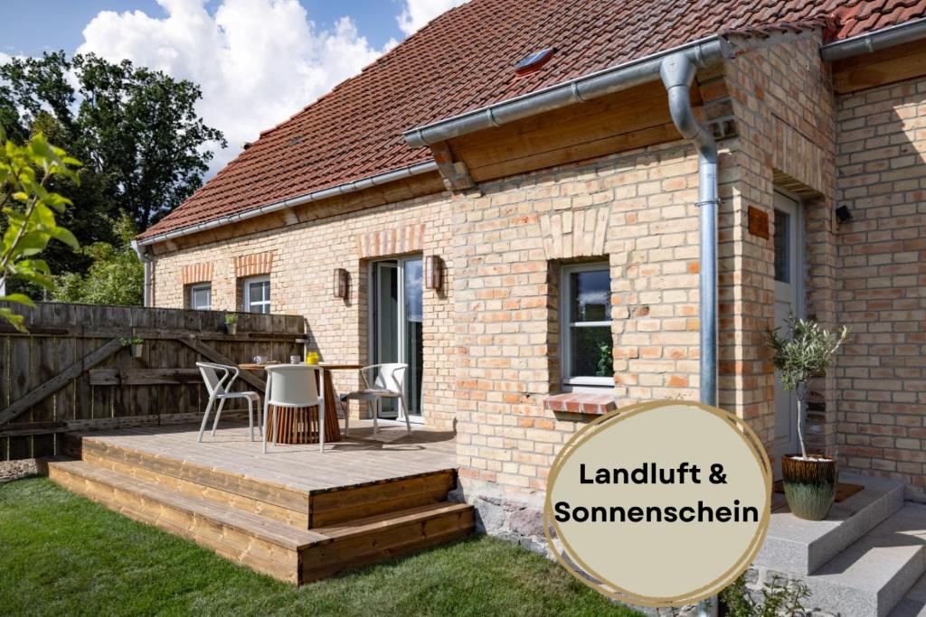a brick house with a patio with a table and chairs at Hufe 9 Gute Stube - Digital Detox und Entschleunigen oder Aktiv-Urlaub in der Natur - Bauernhof Charme trifft modernes Design in Wustrow