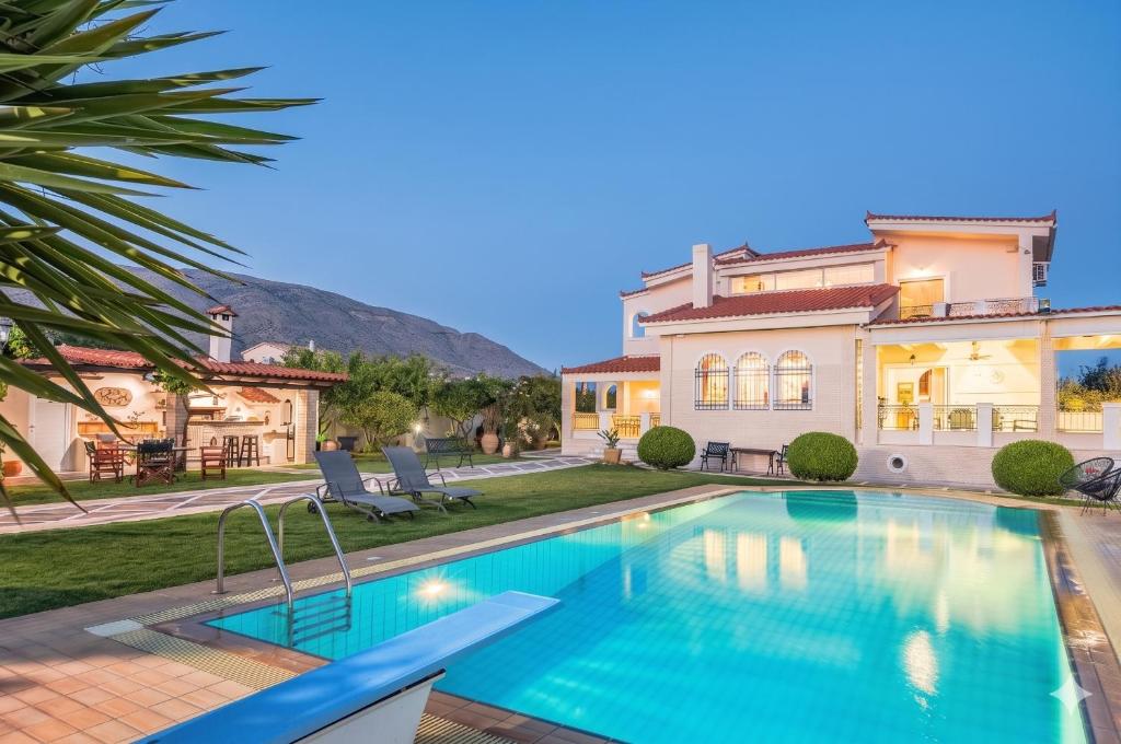 a swimming pool in front of a house at Renko Royal Villa - Private Infinity Pool & Garden - Athens Riviera in Lagonissi