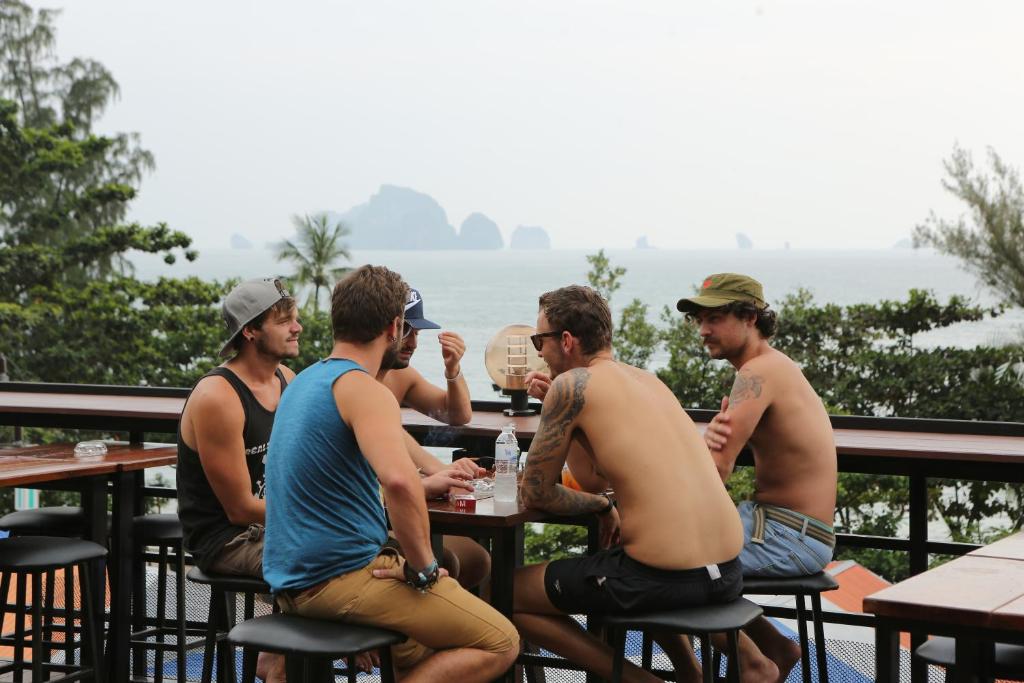 un grupo de hombres sentados en una mesa frente al océano en Balcony Party Hostel - 18-40, en Ao Nang Beach