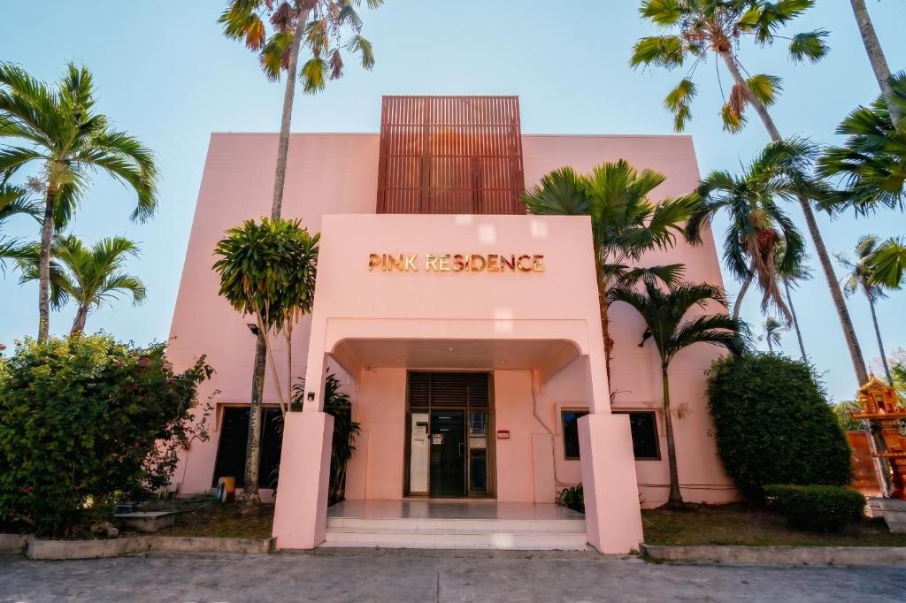 a pink building with palm trees in front of it at Pink Residence Chalong in Ban Bang Chak