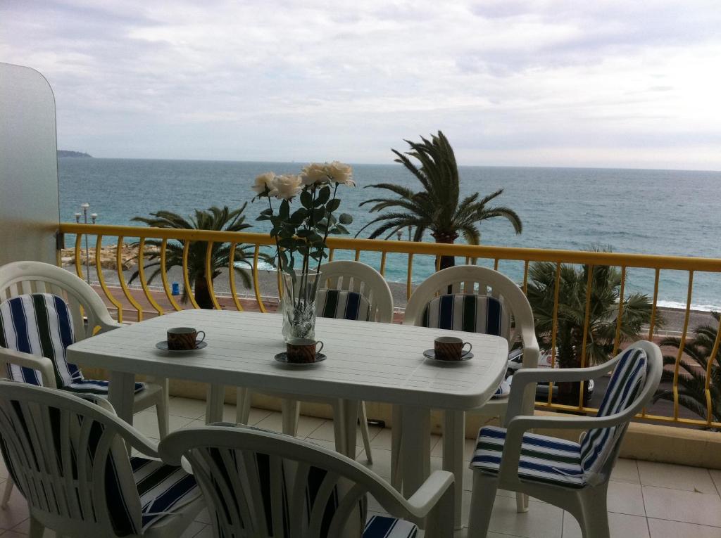 a table with chairs and a vase of flowers on a balcony at Apartment Duplex on Promenade des Anglais 177 in Nice