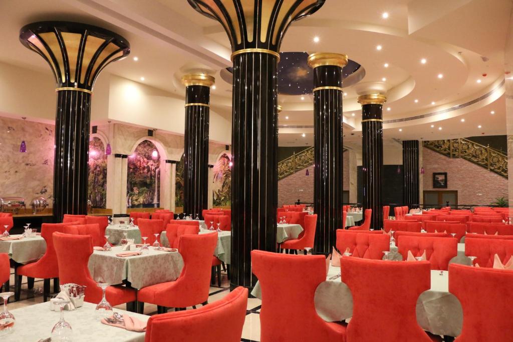 a restaurant with red chairs and tables and columns at Red Castle Hotel in Sharjah