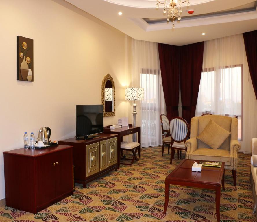 a living room with a television and a room with a table at Red Castle Hotel in Sharjah