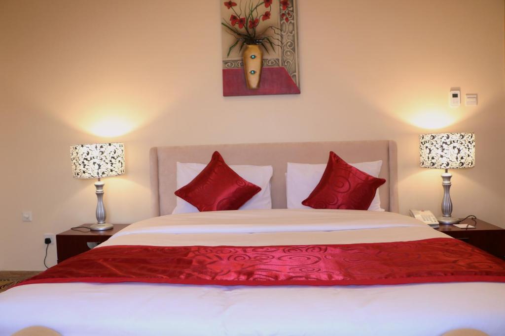a bedroom with a large bed with red pillows at Red Castle Hotel in Sharjah