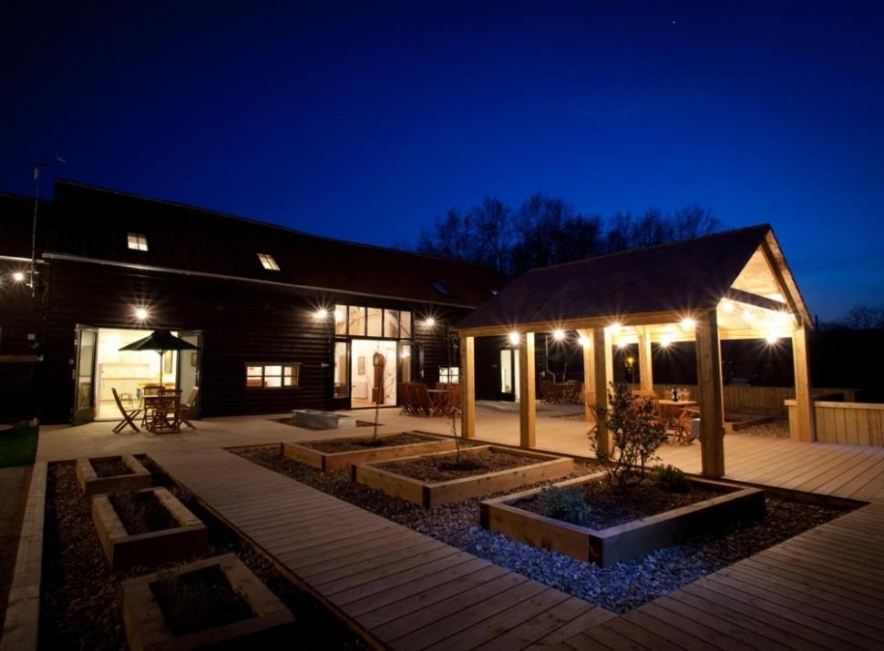 a house with a patio at night with lights at Creeksea Place Barns in Burnham-on-Crouch